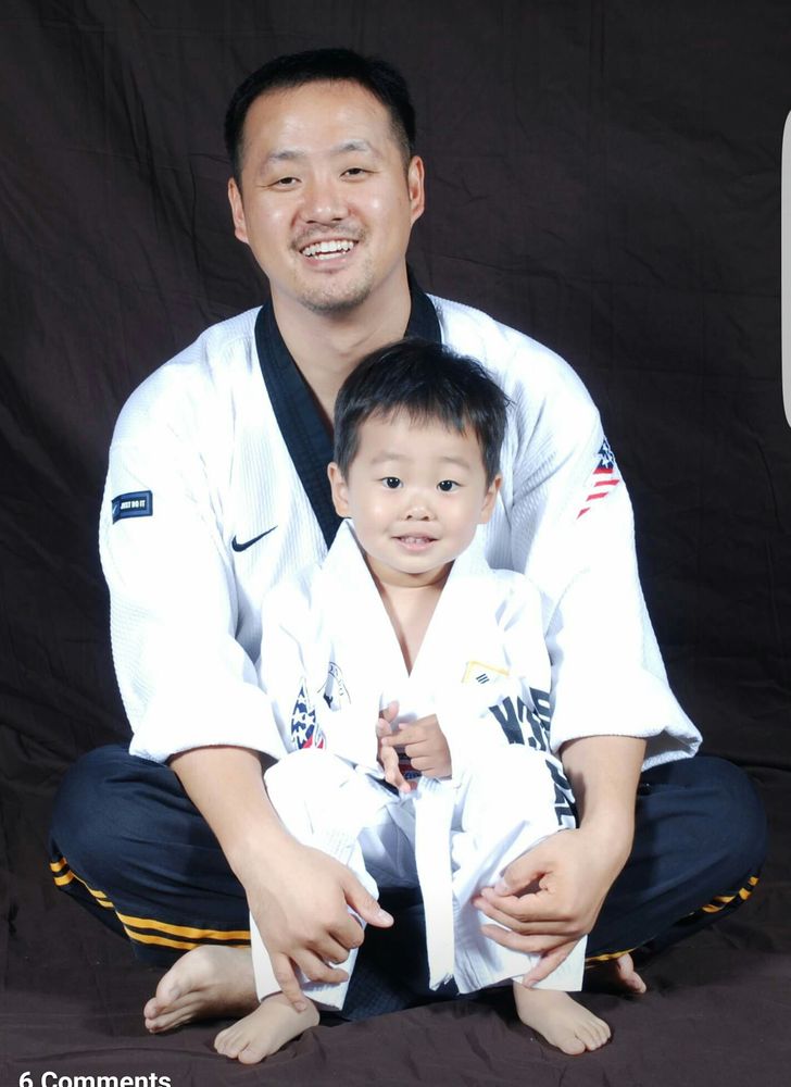 An adult and child in Taekwondo uniforms
